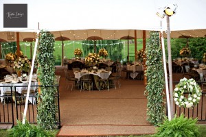tent poles are covered in foliage where the guests will enter the reception