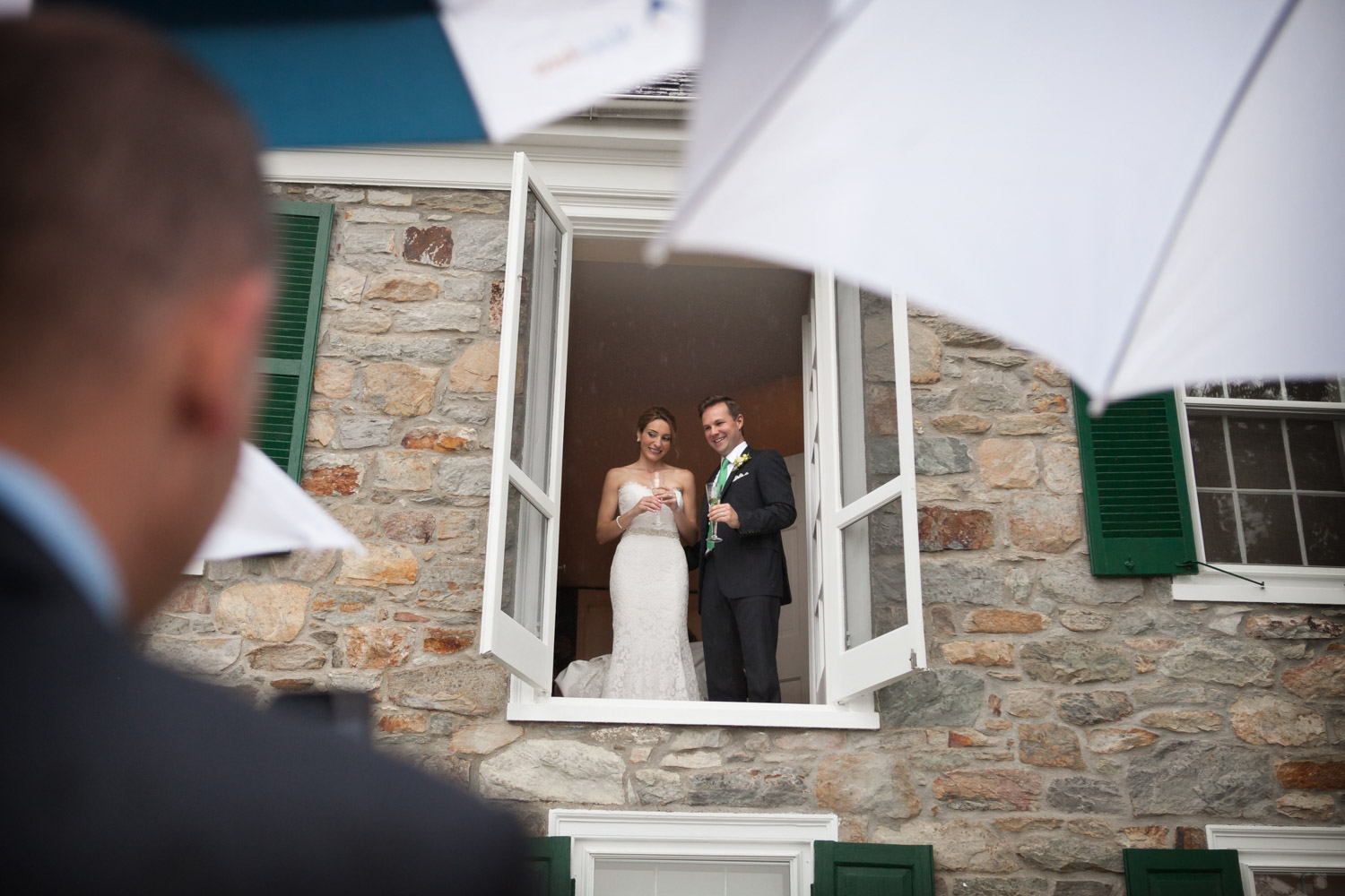 Bride and groom looking out a window during a rainy wedding day, planned by Bellwether Events, Washington DC